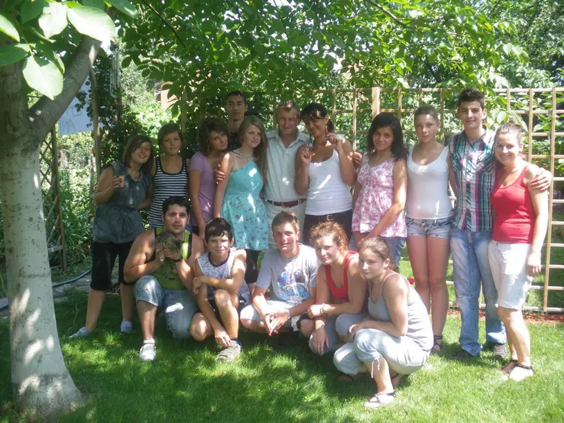 Grup de tineri voluntari într-o grădină, la umbra unui copac